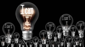 Large group of shining and dimmed light bulbs with fibers in a shape of I Can't and I Can words isolated on black background; concept of Motivation, Positivity and Change