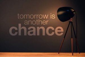 Tomorrow is another chance motivational quote on office wall illuminated by the desk lamp