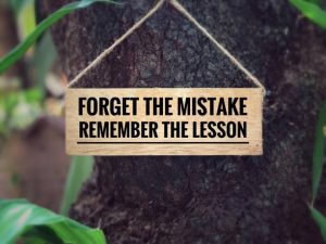 Forget the mistake, remember the lesson? written on a wooden signage. With blurred vintage styled background.