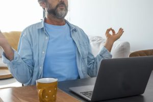 older male doing meditation with yoga mudra in office setting