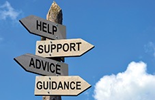 sign saying help, support, advice & guidance pointing in various directions with sky cloud in the background